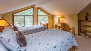 Une chambre avec deux lits, un bureau, une lampe et une bibliothèque.