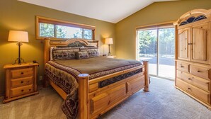 A bedroom with a wooden bed, two bedside tables with lamps, a large wardrobe, and a window with a view of trees. - Topflite 12 (Bend)