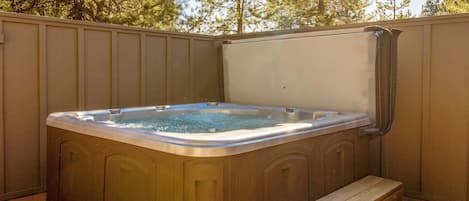 A hot tub with a wooden bench and a wooden deck.
