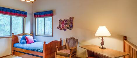 A bedroom with a wooden bed, a chair, a desk, and a lamp.