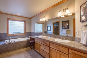 Une salle de bain avec deux lavabos, une baignoire et un grand miroir.