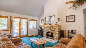 A cozy living room with a stone fireplace, comfortable sofas, and a wooden coffee table. - Warbler 12 (Bend)