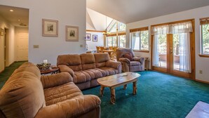 A spacious living room with a sectional sofa, a coffee table, and a dining area with wooden chairs. - Warbler 12 (Bend)