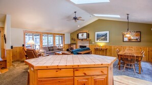 A spacious living area with a wooden dining table, a sofa, and a fireplace. - Whistler 2 (Bend)