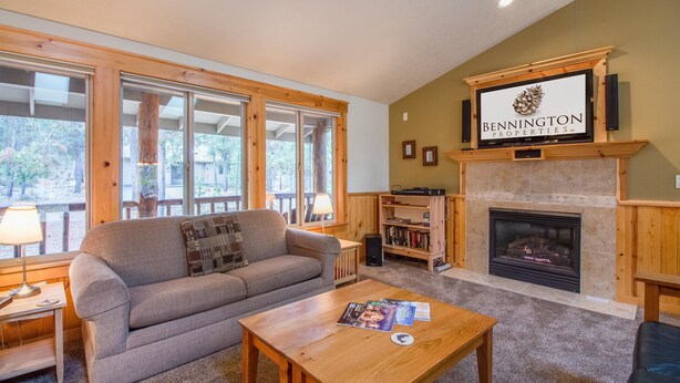 A cozy living room with a fireplace, a sofa, a coffee table, and a bookshelf. - Whistler 2 (Bend)