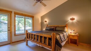 A bedroom with a wooden bed, a nightstand with a lamp, and a ceiling fan. - Whistler 2 (Bend)