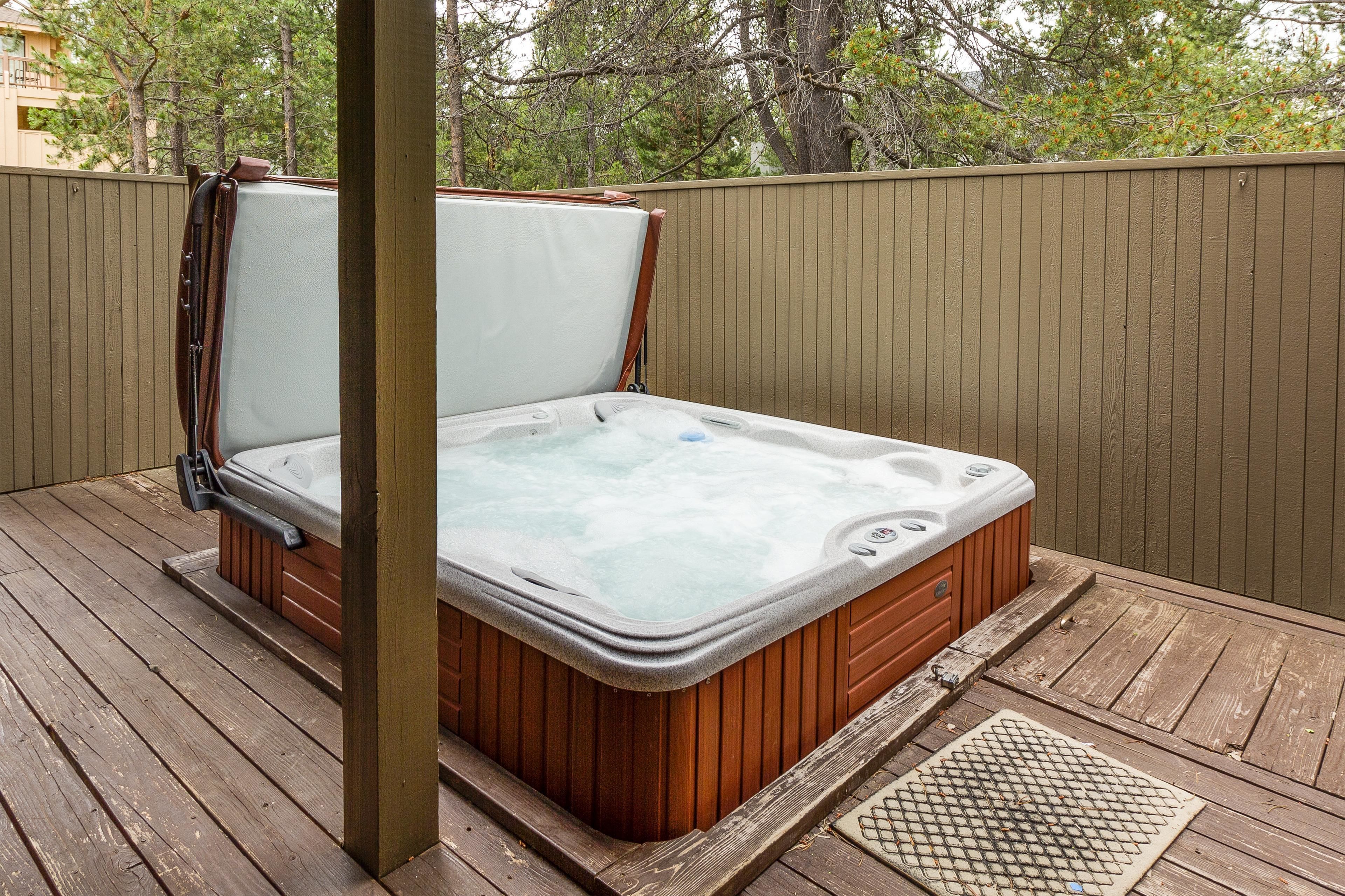 A hot tub on a wooden deck with a wooden fence in the background.