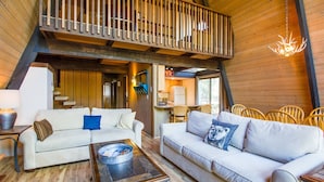A spacious living area with two white sofas, a coffee table, and wooden flooring. - Woodland 1 (Bend)