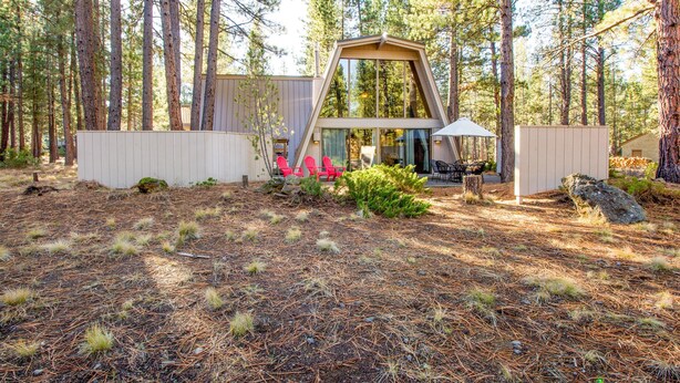 A modern cabin with a triangular roof, surrounded by a forest. - Woodland 1 (Bend)