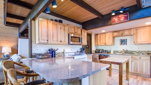 A spacious kitchen with wooden cabinets, a granite countertop, and a central island with seating. - Woodland 1 (Bend)
