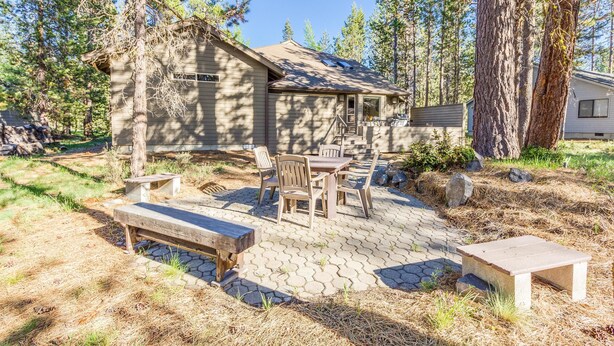 Een chalet met een patio, voorzien van een tafel en stoelen, omringd door bomen.