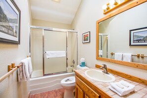 Un baño con ducha, inodoro, lavabo y un espejo grande.