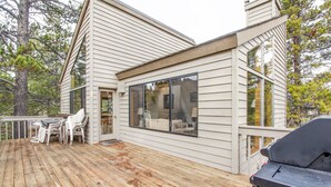 A wooden deck with outdoor furniture, a grill, and a large window overlooking the deck. - Red Alder 3 (Bend)