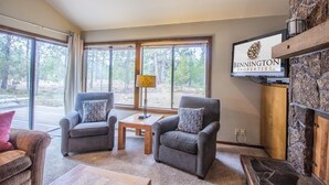 A cozy living room with two grey armchairs, a wooden coffee table, and a stone fireplace. - Alpine 7 (Bend)