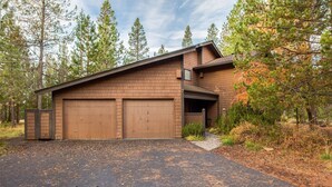 A two-story house with a garage, surrounded by trees and a driveway. - Alpine 7 (Bend)