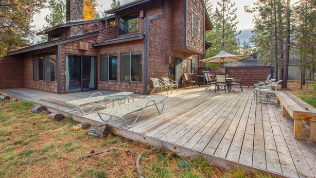 A modern house with a deck, outdoor furniture, and a large umbrella. - Alpine 7 (Bend)