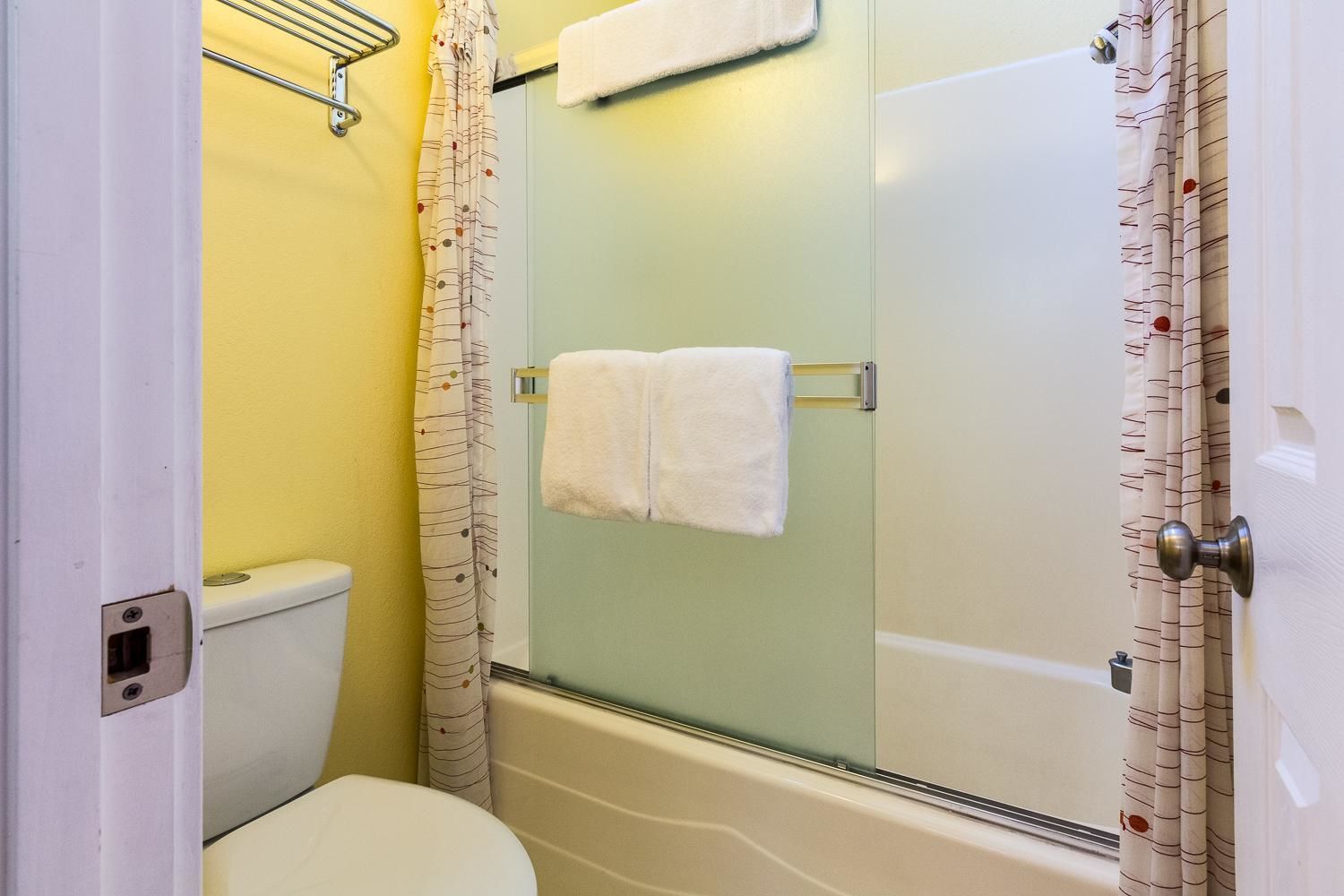 Ein Badezimmer mit Toilette, einer Dusche mit Glastüren und einem Handtuchhalter.