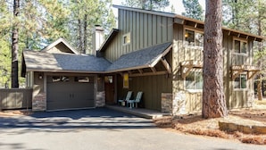 A two-story house with a garage, a covered porch, and a stone foundation.