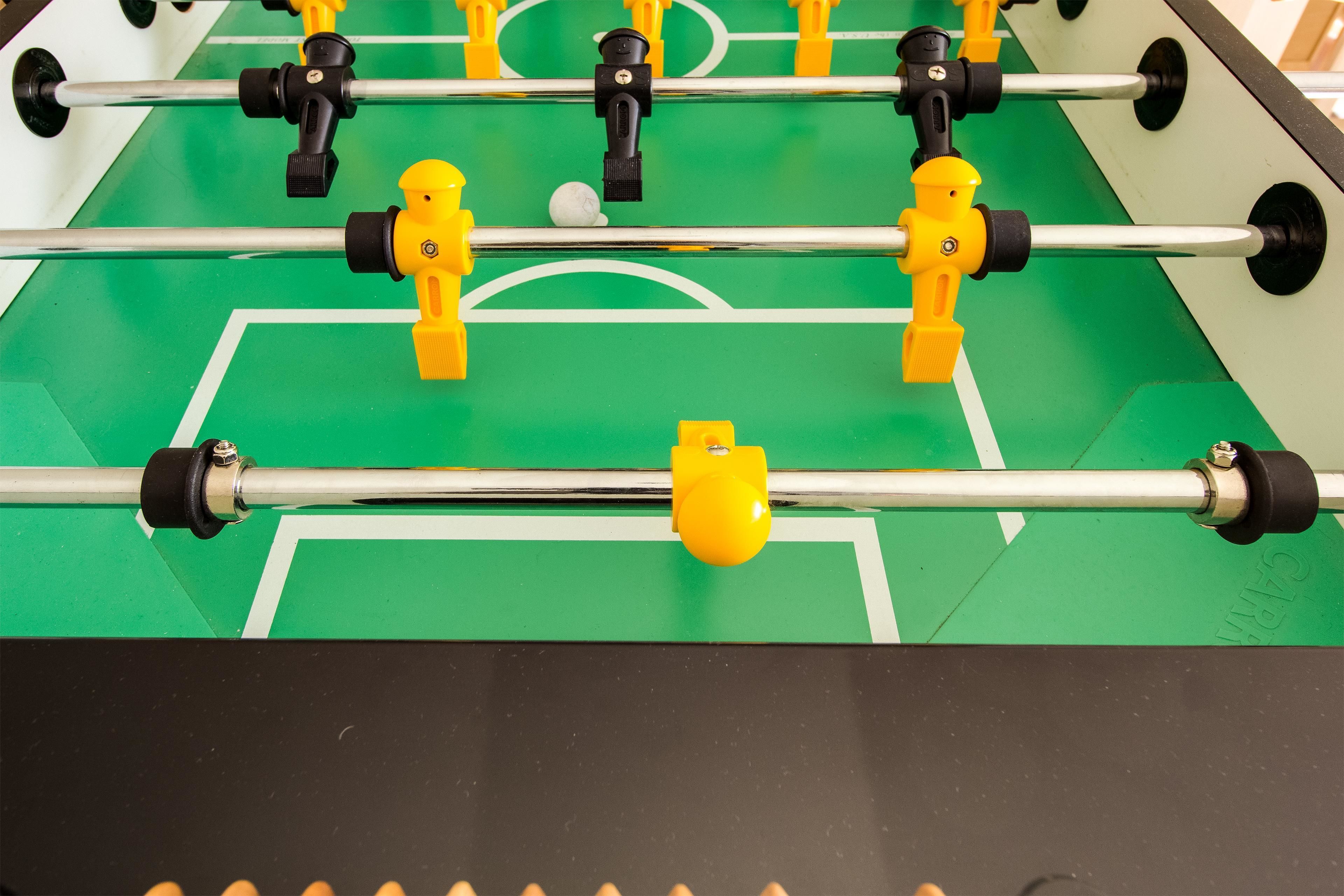 Ein Kicker mit grüner Spielfläche und weißen Linien.