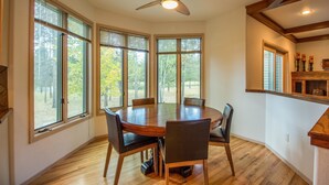 A dining area with a round table, six chairs, and a ceiling fan. - Siskin 12 (Bend)