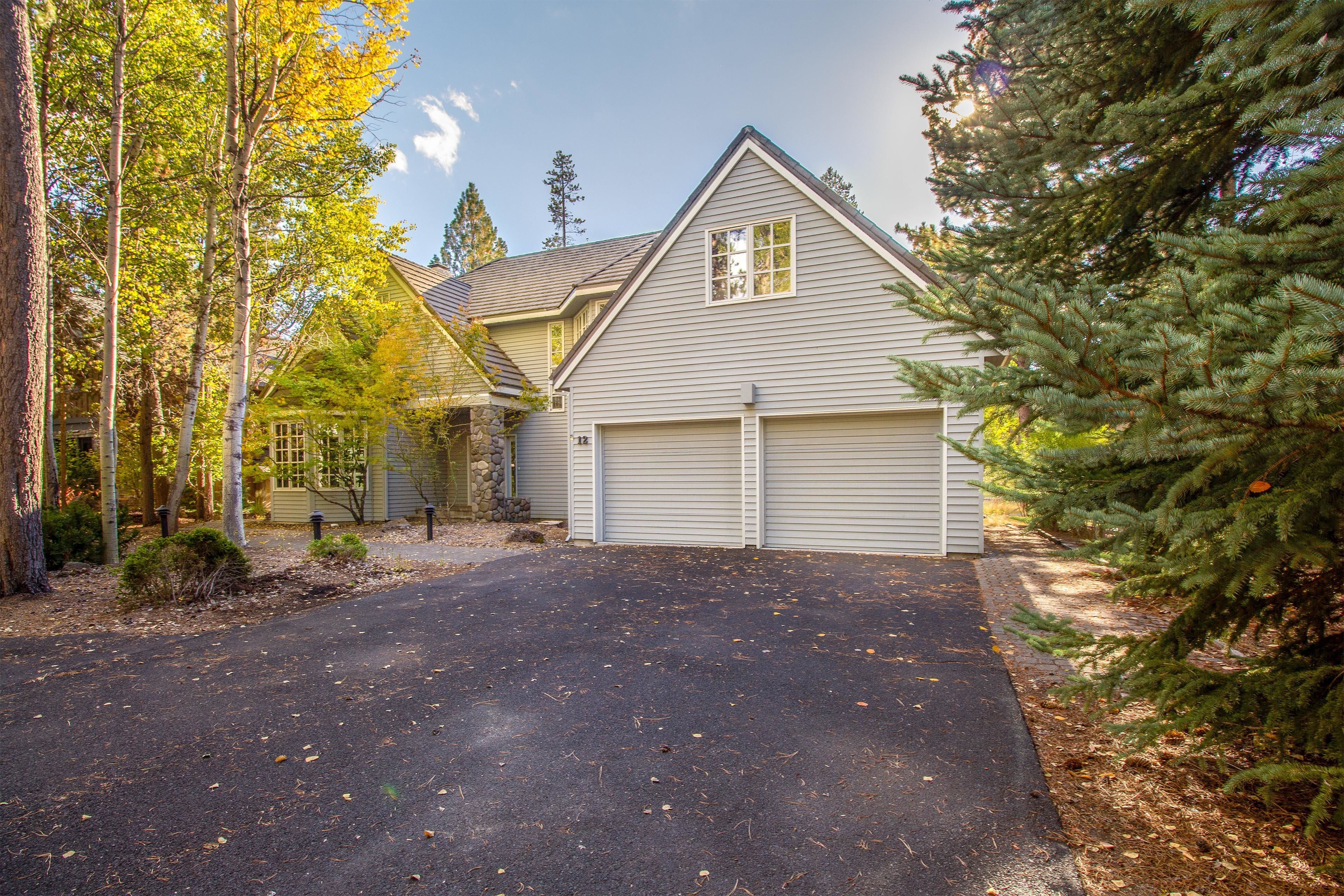 A two-story house with a garage, surrounded by trees and a driveway.