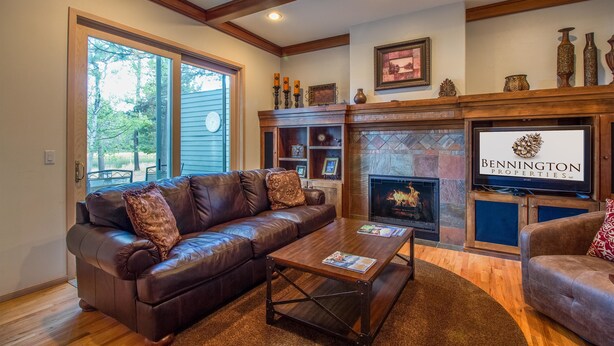 A living room with a leather sofa, coffee table, fireplace, and wooden beams on the ceiling. - Siskin 12 (Bend)