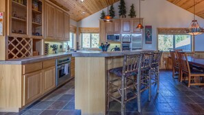 A spacious kitchen with wooden cabinets, a large island, and a dining area with rustic chairs. - Tokatee 30 (Bend)