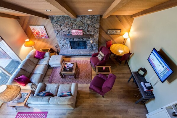 A cozy living room with a stone fireplace, comfortable seating, and a television.