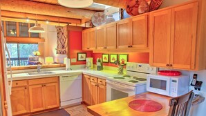 A kitchen with wooden cabinets, a stove, a microwave, and a dining table with a placemat.