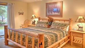 Une chambre confortable avec un lit en bois, une table de chevet, une lampe et un tableau encadré au mur.