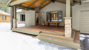 A covered porch with a stone pillar and a bench, leading to a wooden door. - Backwoods 3 (Bend)