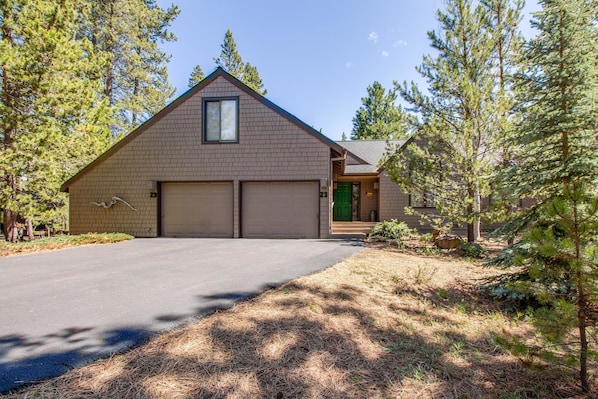 A two-story house with a garage, surrounded by pine trees. - Kinglet 23 (Bend)