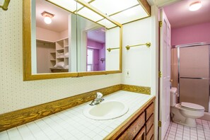 A bathroom with a white sink, wooden vanity, a large mirror, and a shower area. - Kinglet 23 (Bend)