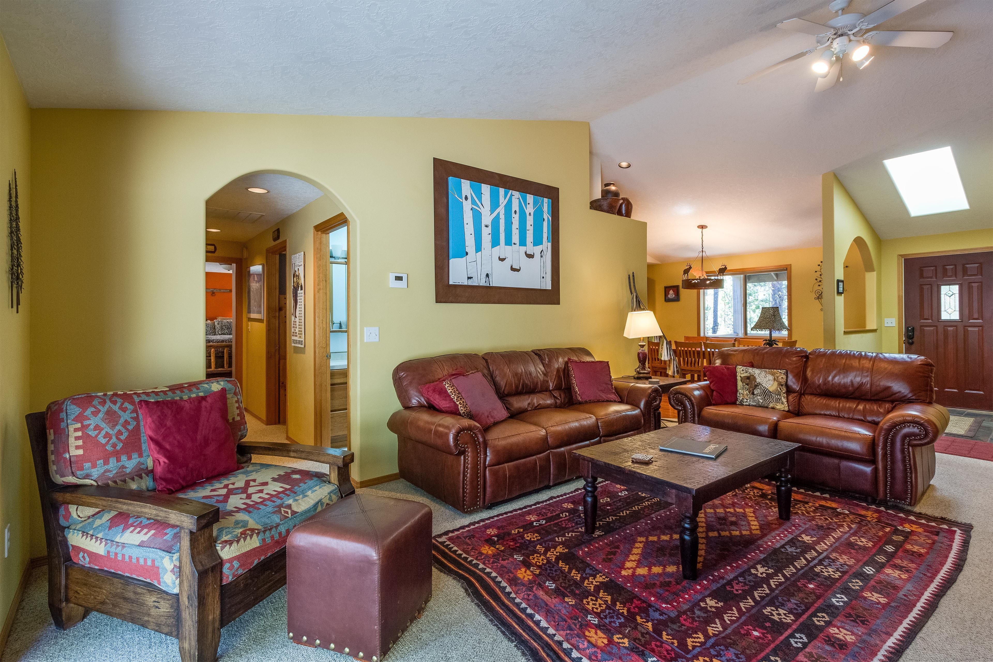 A living room with a brown leather sofa, a patterned armchair, and a coffee table.