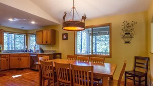 Una cocina amplia con armarios de madera, una mesa de comedor con sillas y un gran ventanal con vistas al exterior.