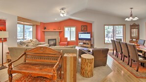 A spacious living room with a fireplace, a television, and a dining area with chairs and a table. - Juniper 18 (Bend)
