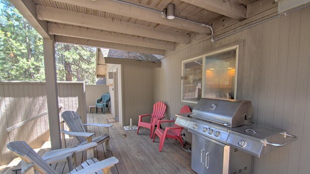 An outdoor patio with a grill, wooden chairs, and a covered area. - Juniper 18 (Bend)