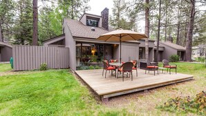 A modern house with a deck, outdoor seating, and a stone fireplace. - Meadow House Cndo 8 (Bend)