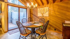A dining area with a wooden ceiling, a chandelier, and a table with chairs. - Meadow House Cndo 8 (Bend)