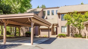 A two-story house with a covered porch and a driveway. - Skyline Condo 13 (Bend)