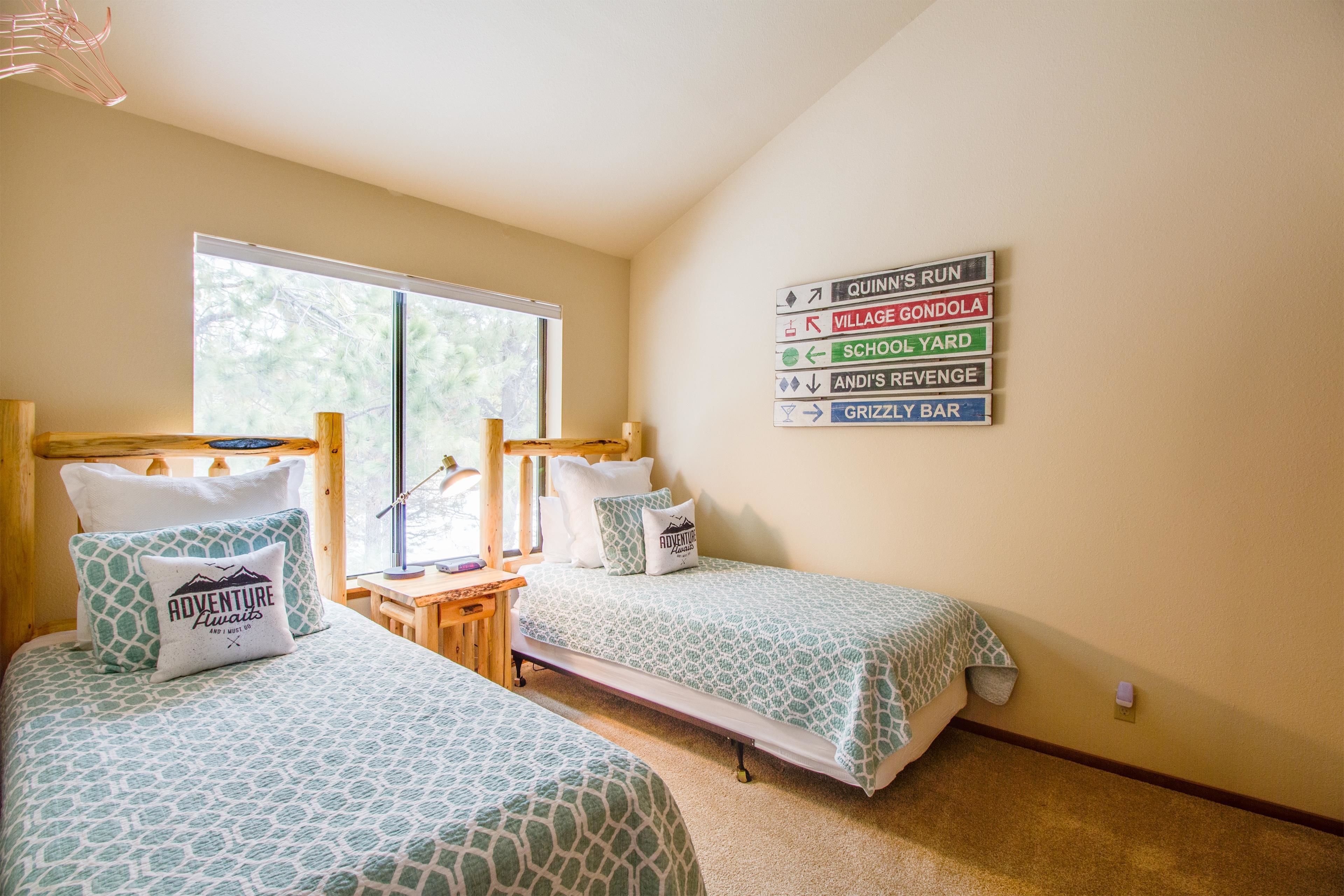 A bedroom with two beds, a window, and a wall sign indicating directions to various locations.