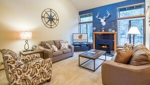A living room with a fireplace, a sofa, a coffee table, and a TV. - Skyline Condo 13 (Bend)