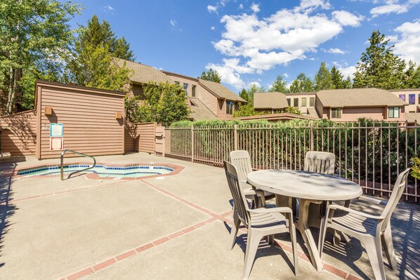 A backyard with a swimming pool, a patio table with chairs, and a wooden fence. - Skyline Condo 13 (Bend)