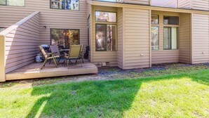 A two-story house with a covered patio area featuring outdoor furniture. - Skyline Condo 13 (Bend)