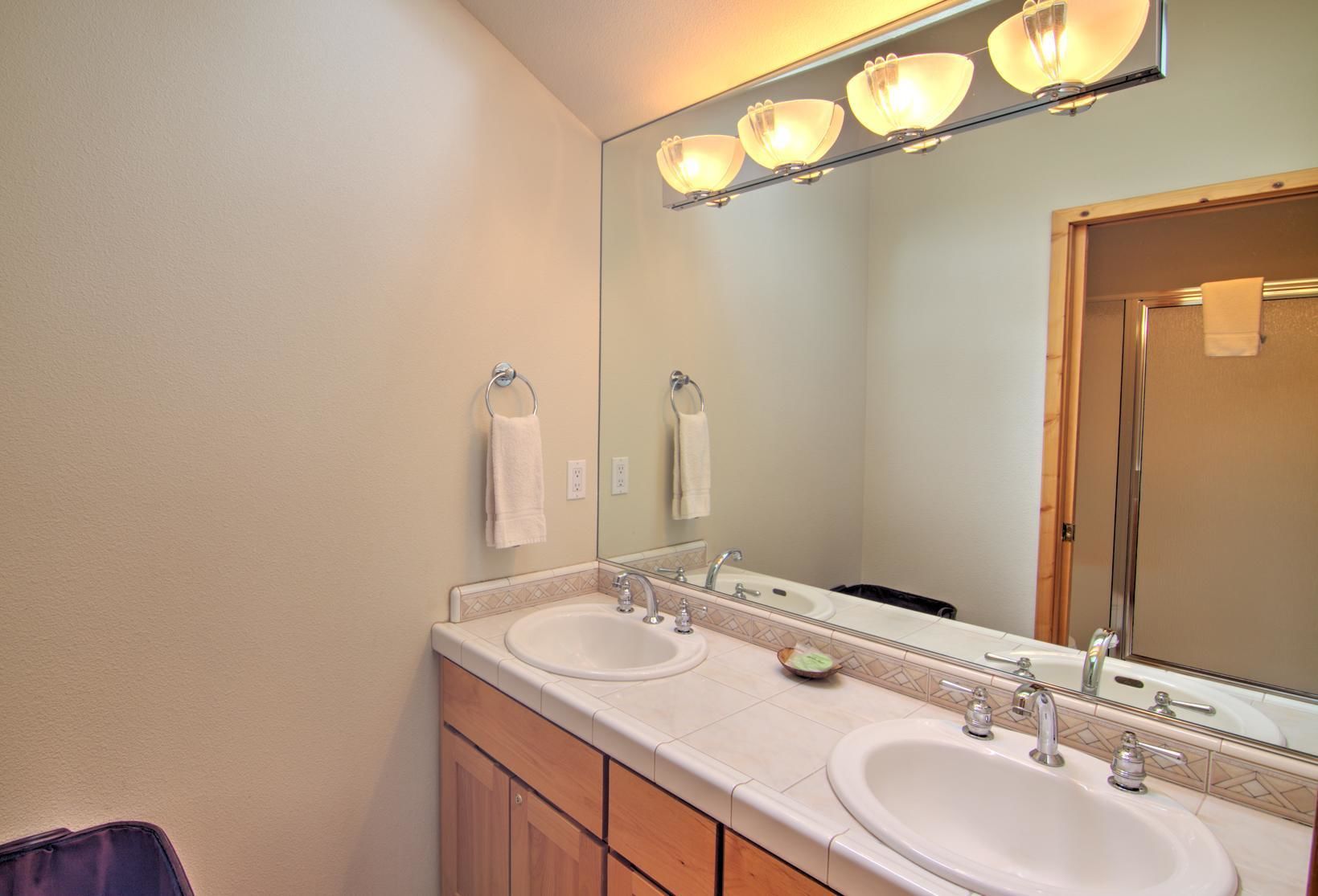 A bathroom with two sinks, a large mirror, and a towel rack.