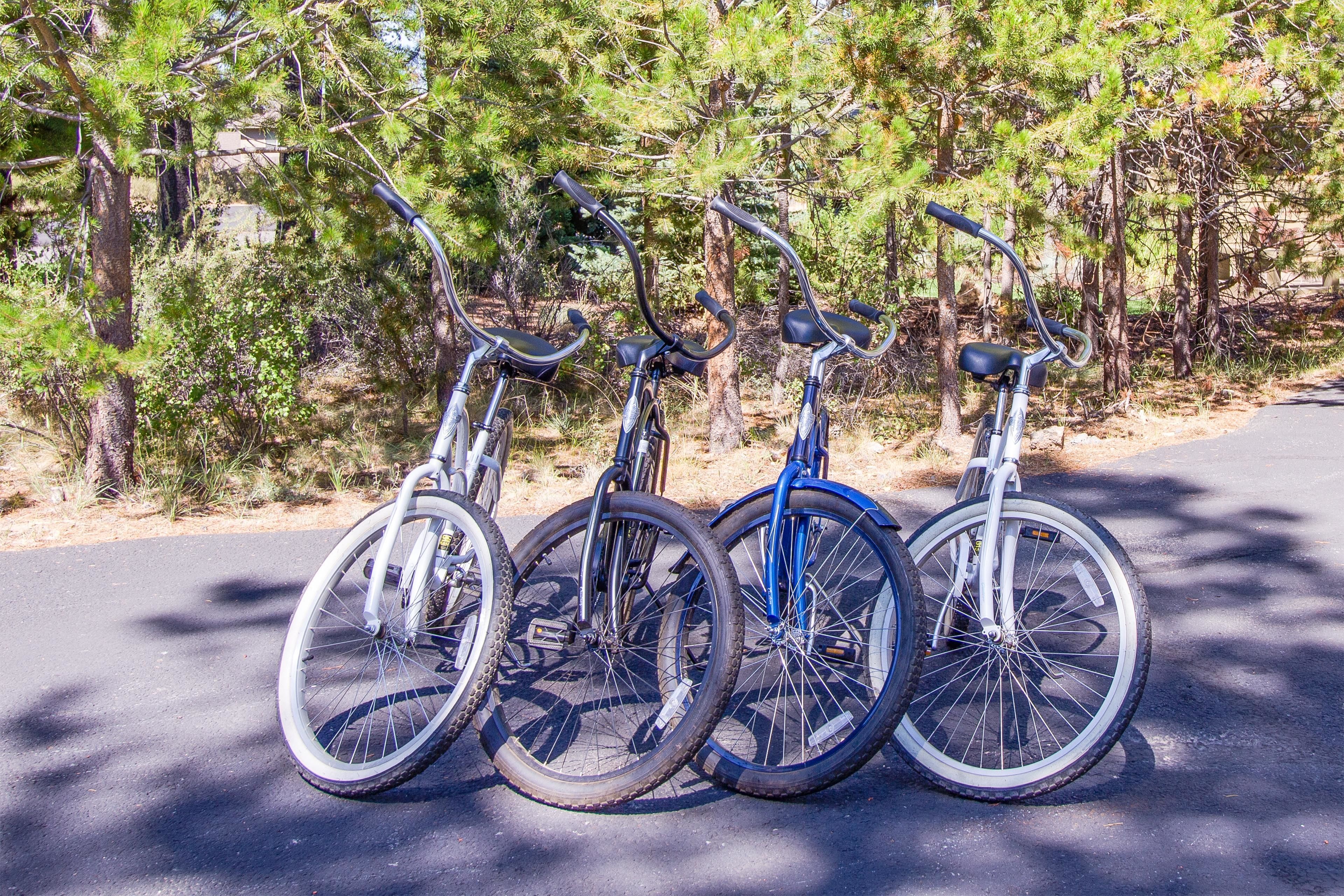 Tres bicicletas estacionadas en un camino pavimentado, con árboles al fondo.
