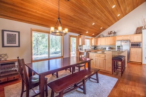 A spacious kitchen with wooden cabinets, a large island, and a dining area with a bench. - Dutchman 17 (Bend)