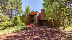 A modern house with a wooden exterior, a driveway, and a well-maintained garden. - Wickiup 14 (Bend)