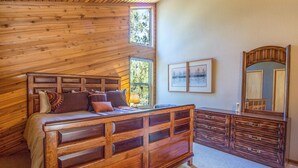 Une chambre à coucher de style cabane en bois, avec un grand lit, une commode et un miroir.