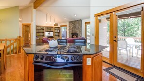 Una cocina moderna con una isla central que tiene estufa, armarios de madera y una zona de comedor con banco y sillas.
